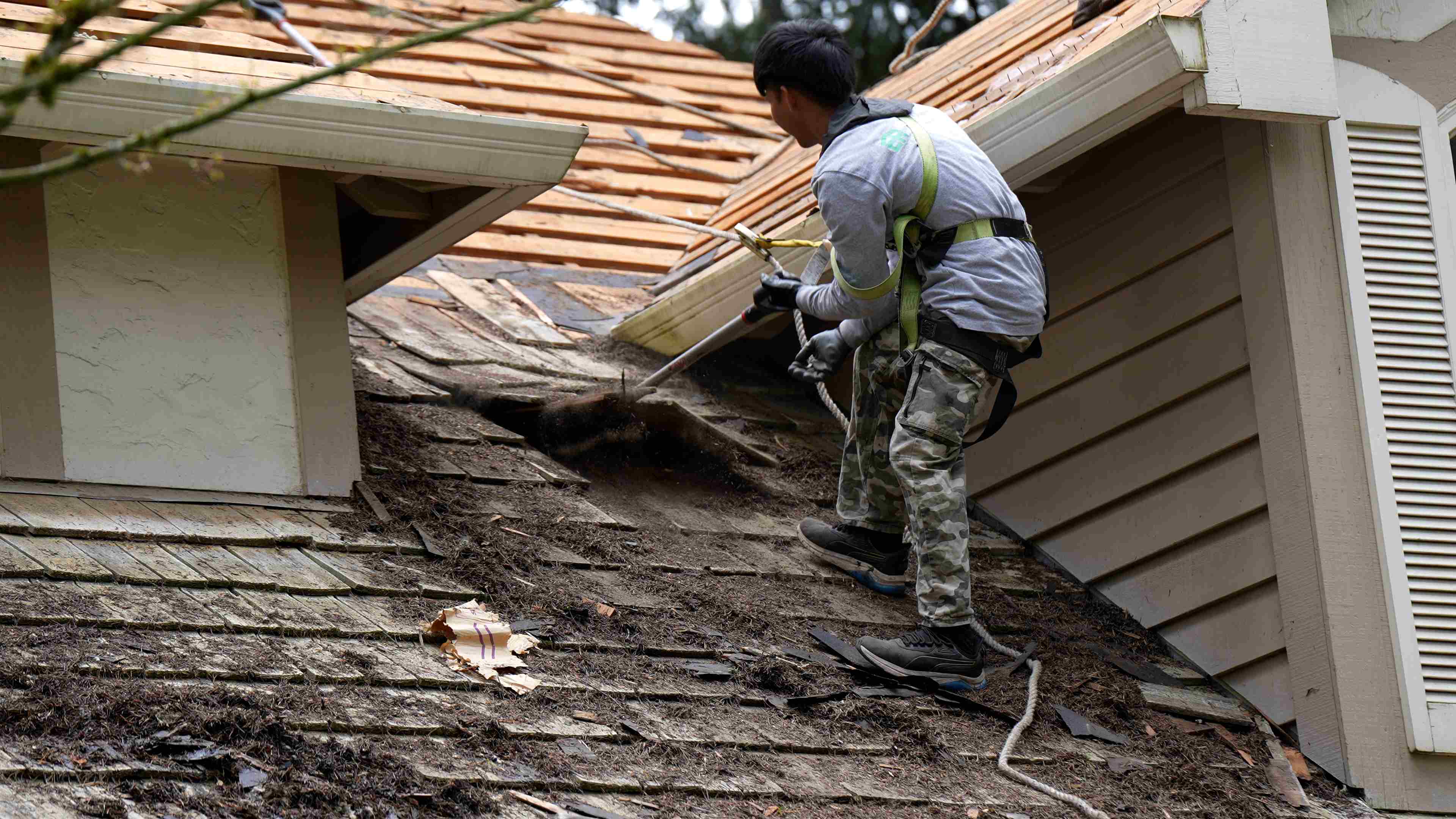 Roofer removing old shingles during roof replacement